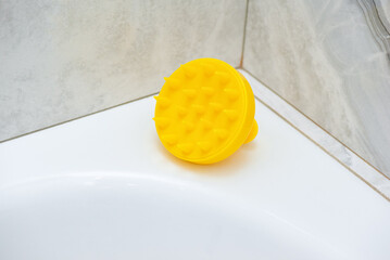 Yellow brush for hair growth stimulating brush. Massage brush in the light bathroom.