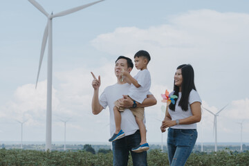 Warm family of parents and children doing holiday activities at wind farm. Alternative energy concept for clean energy.