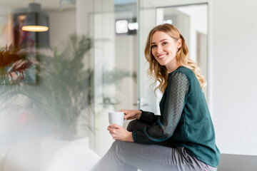 Contented female professional having coffee at office