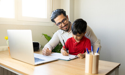 Smiling businessman looking at son writing on clipboard at home