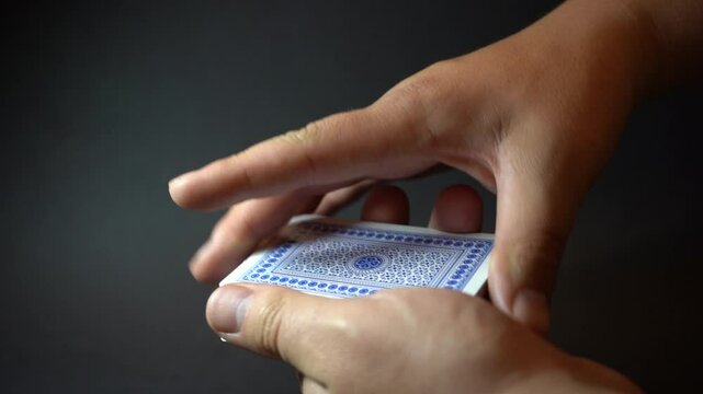 Skilled hands manipulate playing cards with precision and flair, showcasing sleight of hand, tricks, or smooth shuffling in a moment of focus.

