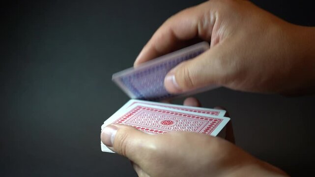 Skilled hands manipulate playing cards with precision and flair, showcasing sleight of hand, tricks, or smooth shuffling in a moment of focus.

