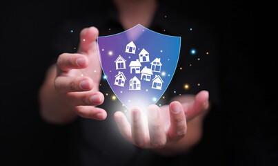 Real estate, house, or property insurance concept. A man holding house icons behind a shield, symbolizing coverage that protects against various risks