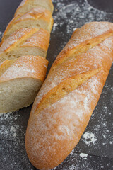 Fresh bread, baguette, loaf on black background, baguette pieces, bread with flour