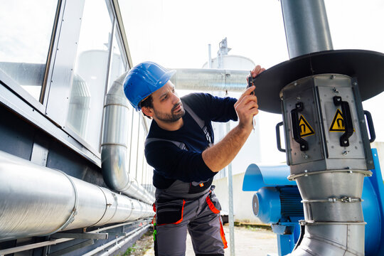 Engineer performing maintenance on industrial equipment outdoors