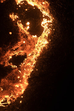 Steel wool sparks create a glowing abstract pattern in the dark