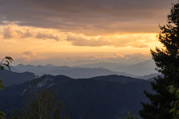 Landscape photo of the mountain range with partly cloudy sky at sunset.