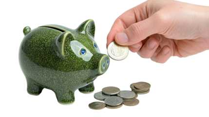 A hand placing coins into a green ceramic piggy bank representing the concept of saving and building personal wealth through financial discipline and planning
