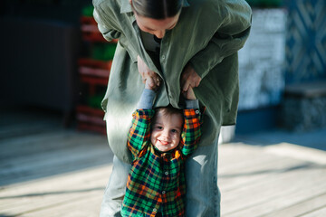 Mom and her son toddler in the park. Mom is holding kid hand, they are walking outdoor. Happy family dream concept. Mother and child together, lifestyle photo.