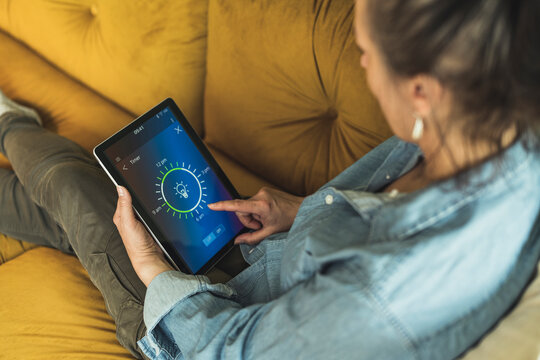 Woman adjusting timer through digital tablet while sitting on sofa at home