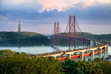 Lisbon 25 de Abril bridge and Christ the King statue at sunset over