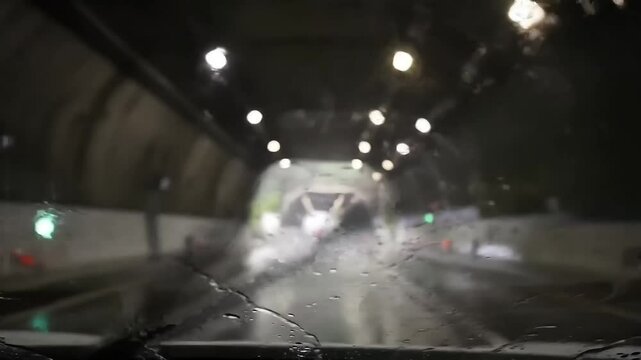 First-Person View in Rainstorm Tunnel &ndash; Blurred Wet Road Reflections & Distant Oncoming Vehicle Glow with Ceiling Drips