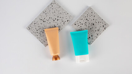 Plastic blue tube for cream or lotion. Skin care or sunscreen cosmetic with stylish props on white background.