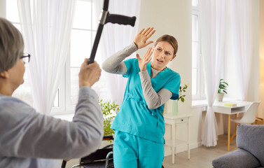 Old patient demonstrates her aggression towards nurse or caregiver, threatens with crutch,...
