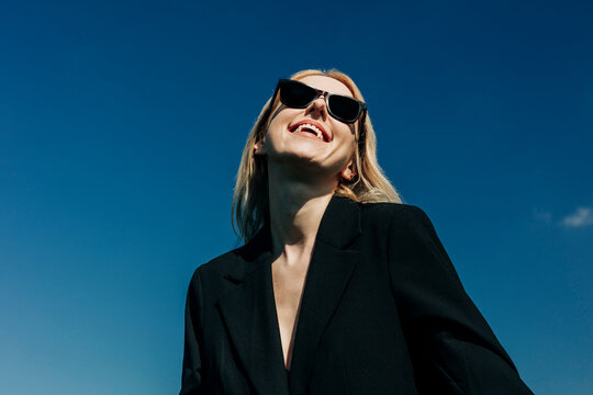Smiling woman in sunglasses under blue sky