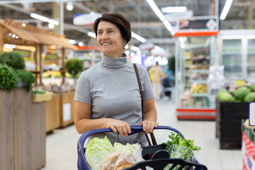 Elderly woman with shopping cart shopping in supermarket