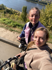 Two girl friends having bicycle ride taking selfie outdoors
