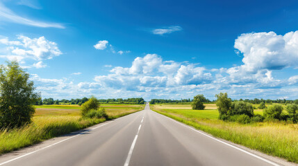 Fototapeta premium Wide road into distance, flanked by green fields and blue sky. High-definition, horizontal composition. Serene beauty.