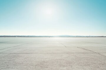 Expansive, light-grey tarmac stretches to a hazy horizon under a bright, mostly clear sky.  A distant, low-lying landmass is barely visible