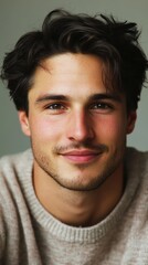 Fototapeta premium Portrait of a Handsome Young Man with Dark Hair and a Gentle Smile Wearing a Beige Sweater