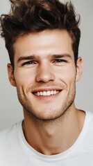 Fototapeta premium Portrait of a Handsome Smiling Young Man with Brown Hair and a White T-Shirt Close-Up Studio Shot