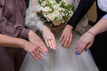 Bride with white rose bouquet showing manicured hands with bridesmaids,symbol of love,unity,joy and...