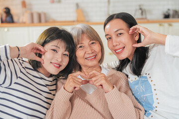 senior woman, her daughter and her granddaughter sitting on the sofa at home Asian family lifestyle...