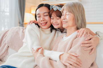 Asian multigenerational family grandmom mother and daughter nephew offspring and granddaughter smiling happily together at camera on sofa The love of a family makes life beautiful	