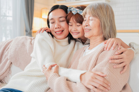 Asian multigenerational family grandmom mother and daughter nephew offspring and granddaughter smiling happily together at camera on sofa The love of a family makes life beautiful	
