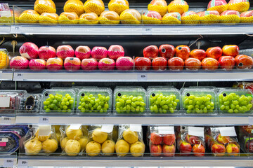 Packaged fruits on supermarket refrigerated shelves including grapes, apples, pears, organized for sale, promoting freshness, nutrition and healthy choices. Food retail in grocery store in Thailand
