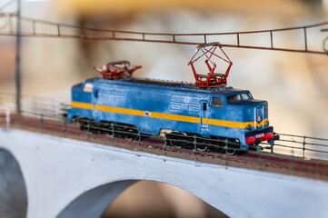 Vintage blue and yellow electric locomotive model crossing bridge
