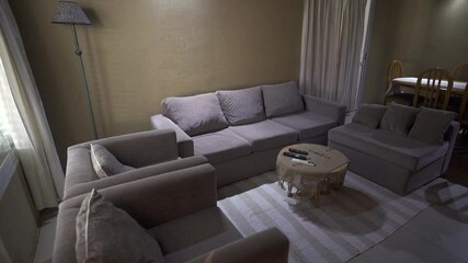 Alternate panning view of cozy wooden house living and dining room, with couch and surroundings in grey and brown tones. Shot on 4K.