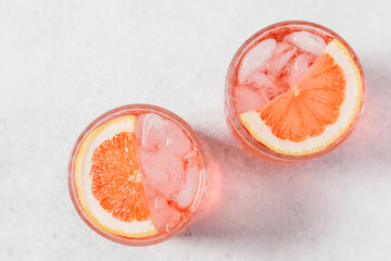 Grapefruit paloma cocktails garnished with citrus slices served in textured crystal glasses on a...