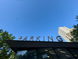 PARKING sign on the roof. Metallic letters text on blue sky background