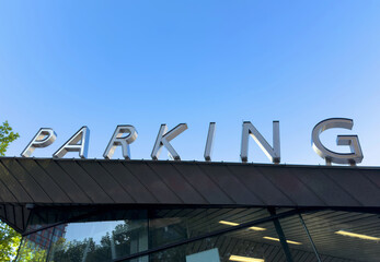 PARKING sign on the roof. Metallic letters text on blue sky background
