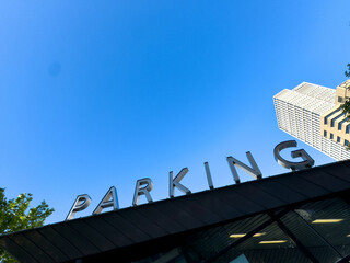 PARKING sign on the roof. Metallic letters text on blue sky background