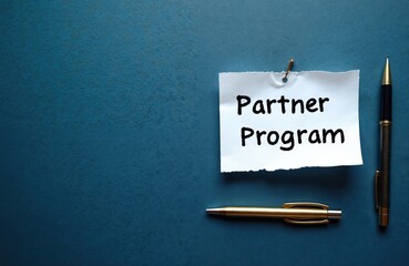 Partner Program message written on white paper with pen on blue background. Conceptual partner program symbol. Partnership opportunities for affiliate marketing, collaboration, business growth. Top