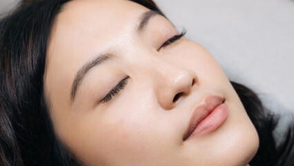 Young southeast asian woman receives eyelashes extension procedure beauty salon. Enhancing natural beauty, female eyes appear longer. Procedure promotes health wellness as form of makeup