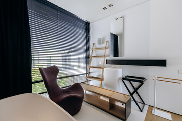 A cozy room with a simple chair and a tall ladder positioned in it