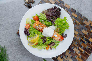 Healthy salmon salad with mixed greens, grilled salmon, cherry tomatoes, and lemon. A light and fresh dish perfect for healthy eating and food photography.