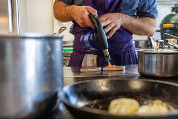 Cuisiniers en pleine préparation dans une cuisine professionnelle, entourés d’ingrédients frais et d’ustensiles de cuisine.