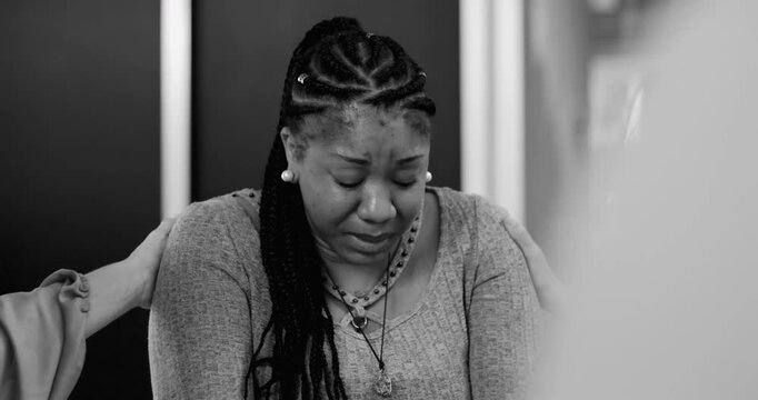Tearful woman receiving comfort during emotional therapy session, group members reaching out in powerful moment of shared vulnerability, black and white