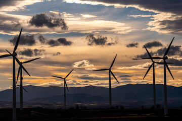 Sunset over wind farm in Zaragoza with wind turbines and clouds, ideal for green energy, environmental themes, and renewable energy industry stock photography.