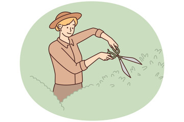 Woman gardener uses large scissors to shape bushes and remove diseased twigs