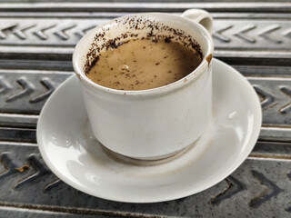 A cup of hot black coffee, served in an outdoor cafe.