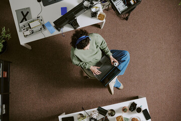 Overhead view of person using laptop in well-organized office setting, surrounded by various...