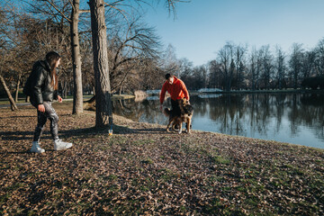 A couple spends quality time walking in a scenic park during sunset, alongside a calm lake,...