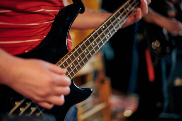 Focused view of musician hand playing bass guitar during performance, highlighting strings and...