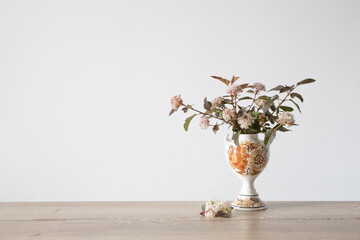 spirea flowers in vintage ceramic vase on background white wall