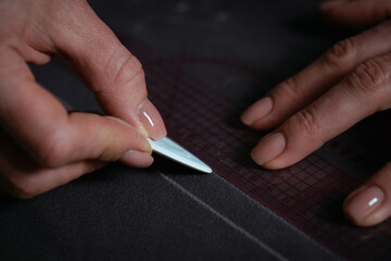 Detailed close-up photograph showing hands guiding fabric through an industrial sewing machine. The image captures the precision and craftsmanship involved in textile production and tailoring. Ideal f